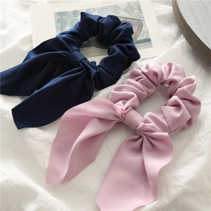 Detail shot of navy and pink ribbon scrunchies with bow design on white fabric