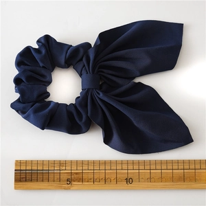 Detail view of navy blue rabbit ear scrunchie with a 15cm measurement ruler for scale