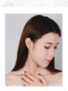 Close-up of a silver astronaut stud earring with a black enamel visor on a female model