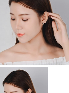 Close-up of silver astronaut stud earrings with black enamel detail on model's ear
