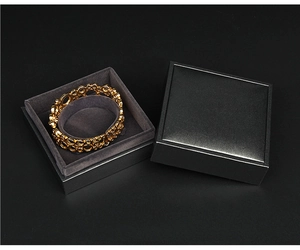 Detail of a hollow golden bangle in a black velvet lined gift box with an open lid