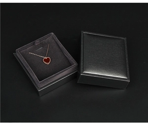 Detail of a black leather jewelry box showing a gold necklace with a red heart pendant