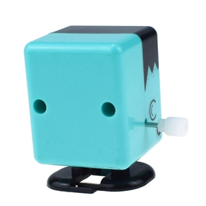Detail of teal square wind-up monster toy with white winding knob and walking base