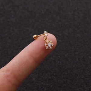 Macro shot of gold stainless steel stud earrings featuring a sparkling zircon flower charm
