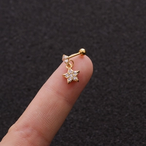 Close-up of a gold star-shaped stud earring with cubic zirconia held on a fingertip