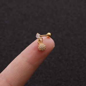 Macro detail of gold earring with cubic zirconia studs held between fingertips