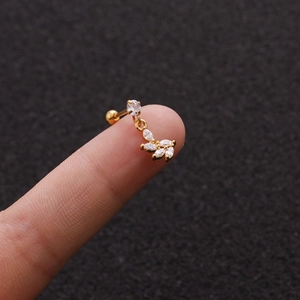Macro view of gold leaf-shaped cartilage stud earring with cubic zirconia marquise stones