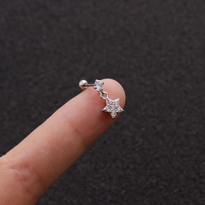 Macro shot of silver cartilage stud with cz star pendant held on a fingertip