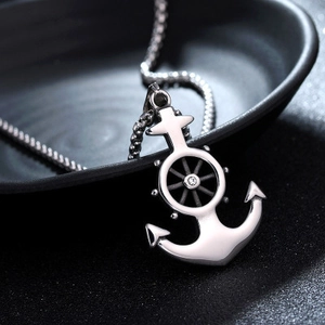 Macro shot of silver anchor and helm pendant with central stone on a metal chain
