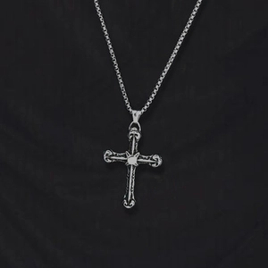 Macro shot of silver vintage cross pendant with textured engravings on a box chain