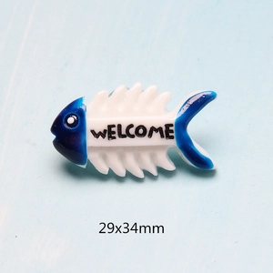 Detailed close-up of blue and white resin fishbone accessory with Welcome text and 29x34mm size