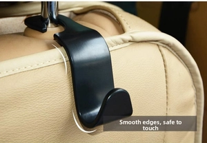 Close-up of black car headrest hook with rounded edges installed on a beige leather seat