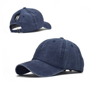 Detail of dark blue washed cotton baseball cap featuring ponytail hole and metal buckle