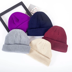 Detailed close-up showing knitting texture of folded beanies in five assorted colors