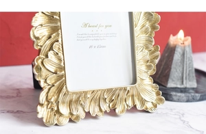 Detail of vintage gold feather relief on a 10x15cm picture frame with warm candlelight