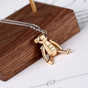 Close-up of a 3D gold bear pendant with a fine silver chain on a dark wooden display
