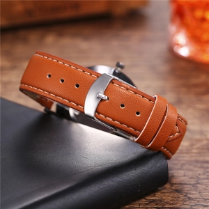Detail shot of brown leather watch strap with white stitching and silver metal buckle