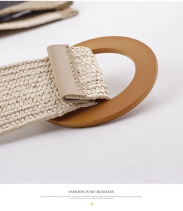 Detail of woven straw belt featuring a round wooden-style buckle and leather trim finish