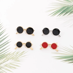 Detail view of stylish sunglasses brooches in gold and silver frames on palm leaves