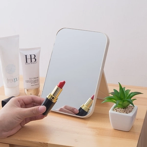 Portable folding desktop makeup mirror with white frame on a minimalist wooden table