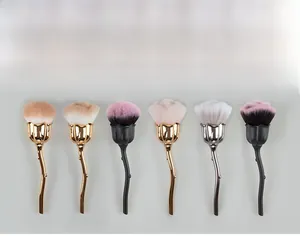 Close-up of rose-shaped makeup brushes with metallic flower stem handles and soft bristles