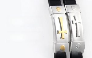 Detail of polished stainless steel plate with golden and silver cross on black wristband