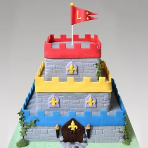 Three-tier castle fondant cake featuring realistic gray stone wall texture and brick patterns