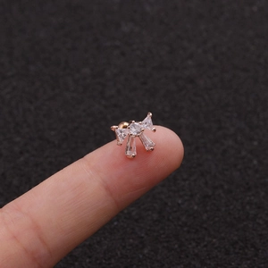 Macro view of tiny rose gold bow stud earring with zircons held on a fingertip