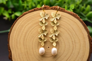 Detail of vintage gold flower drop earrings with white pearls on a rustic wood background