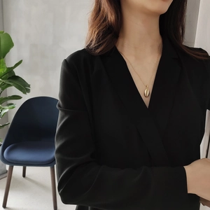 Elegant gold shell pendant necklace on a delicate chain worn by a model in black dress