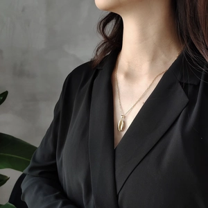 Close-up of a 925 silver golden cowrie shell pendant necklace on a fashion model