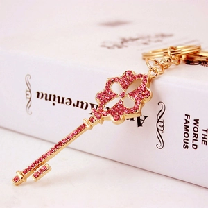Sparkling gold four-leaf clover key pendant with pink rhinestones on a book