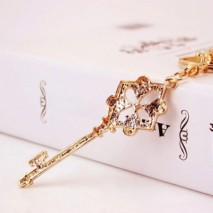 Elegant gold metal clover key pendant with intricate hollow design on white book background