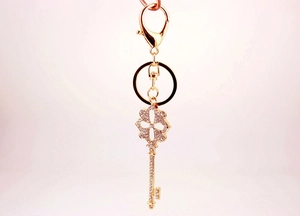 Detailed view of a golden four-leaf clover keychain with sparkling crystals and lobster clasp