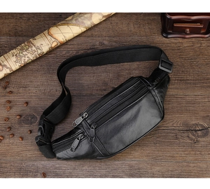 Detail of black waterproof leather waist bag with multiple zipper pockets on wood table