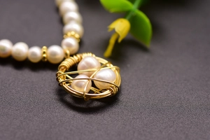 Macro shot of handmade golden wire bird nest pendant with white pearls on a necklace
