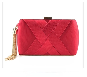 Macro view of red satin clutch bag featuring pleated texture and gold tassel detail