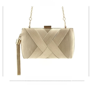 Detail of light gold satin clutch bag featuring pleated fabric and long metal tassels
