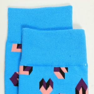 Gros plan du revers de chaussette bleue en coton avec motifs géométriques de cœurs roses