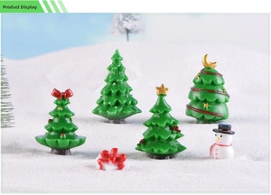 Close-up of miniature Christmas tree set with snowman and gift box on artificial snow
