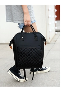 Detail of black nylon diaper bag featuring quilted texture and durable metal rivets