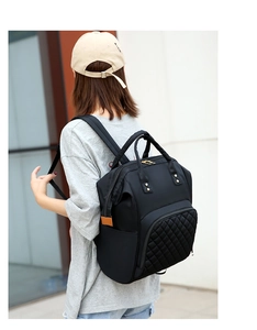 Rear view of a black nylon diaper backpack with gold zippers and quilted front pocket