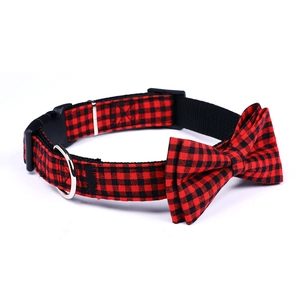Detail of red and black plaid dog collar with bow tie, buckle, and D-ring on white back