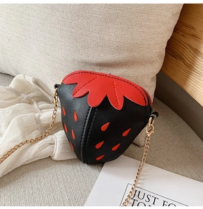 Detail der süßen schwarzen Erdbeer-Umhängetasche mit roten Samen und goldener Kette