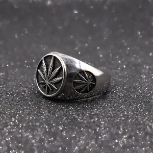 Macro shot of silver stainless steel ring with embossed cannabis leaf designs on black glitter