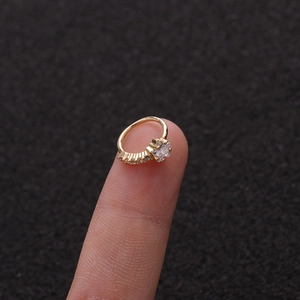 Macro shot of a small gold star-shaped micro-pave zircon piercing ring held on fingertips