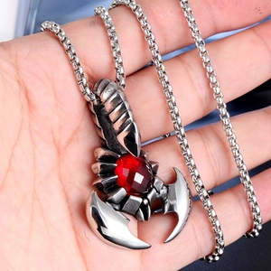 Detail of silver stainless steel scorpion pendant with a red ruby stone on a box chain