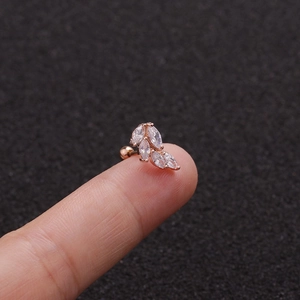 Macro view of rose gold leaf ear stud with clear zircons held on a fingertip