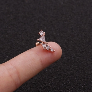 Detailed view of a rose gold leaf and star stud earring with zircon on a fingertip