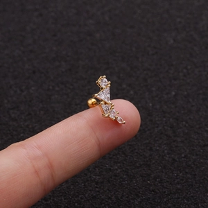 Detailed close-up of a tiny gold leaf ear stud with white zircons held on a fingertip